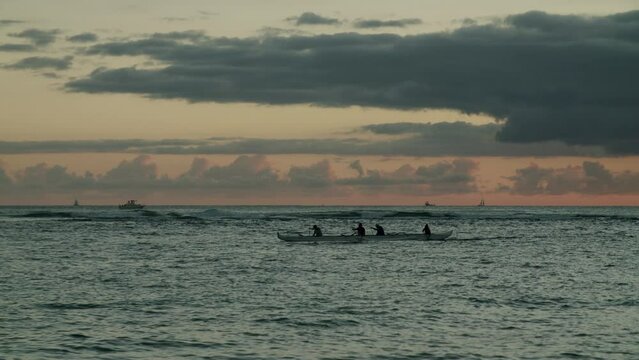 Sunset scenery on the sea of Waikiki Beach with four people paddling  in Honolulu, Hawaii