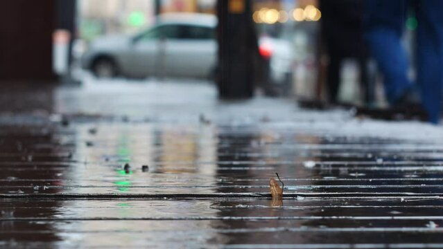 It's raining in the city with wooden sidewalks on the street. In the background you can see a road with cars.