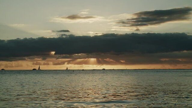 Sunset scenery on the sea of Waikiki Beach with boats sailing in the distant background in Hawaii