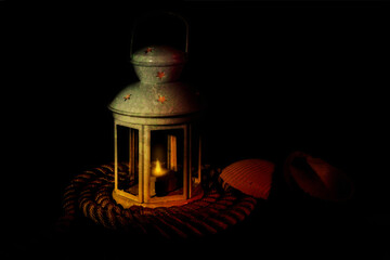 A Small metal maritime lantern with cut-out stars with LED candle on a pile of rope with seashells...