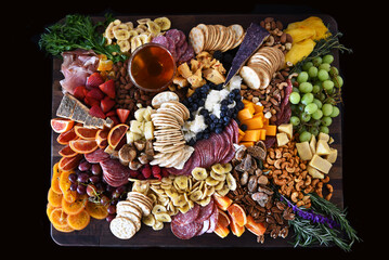 High angle shot of a Charcuterie Board with a mixture of fruits, vegetables, meats and cheeses.
