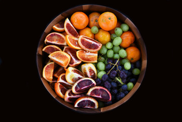 High angle shot of a wooden bowl full of  assorted fruits.