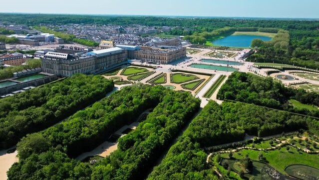 Aerial view of Immense French palace with gilded apartments, chandeliered Hall of Mirrors and fountain show. Fortress castle, Palace of Versailles drone aerial view with landscaped gardens in France.