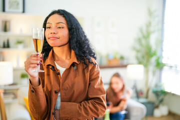 A radiant woman with a warm smile holding a champagne flute, exuding elegance and joy at a casual social gathering.