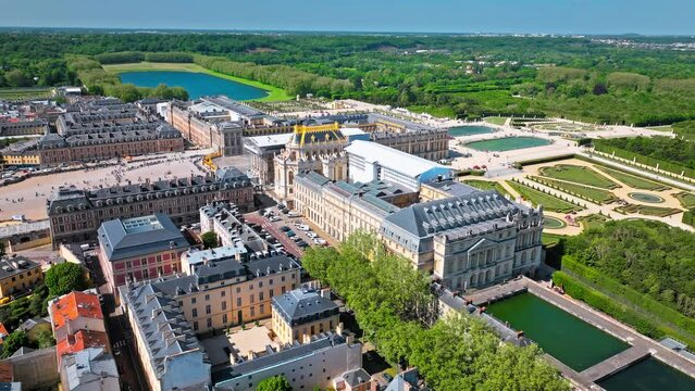 Aerial view of Immense French palace with gilded apartments, chandeliered Hall of Mirrors and fountain show. Fortress castle, Palace of Versailles drone aerial view with landscaped gardens in France.