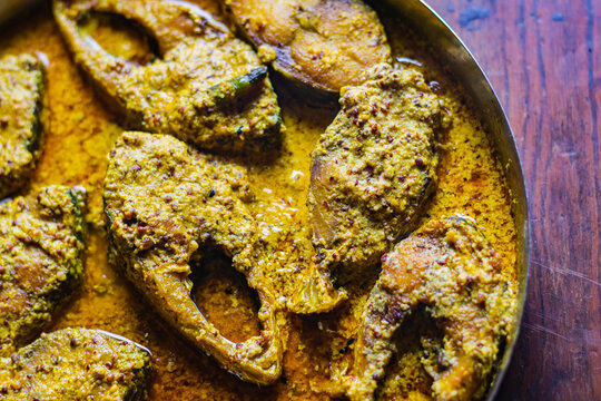 Sorshe ilish or hilsa fish curry cooked with mustard seeds served on a plate. Pieces of fish are seen in rich yellow gravy. This is very popular traditional delicacy in Bengali culture.