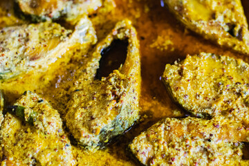 Sorshe ilish or hilsa fish curry cooked with mustard seeds served on a plate. Pieces of fish are...