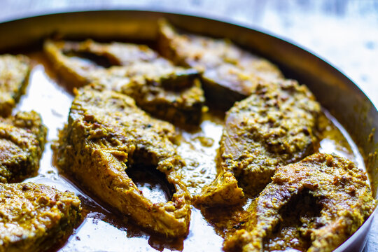 Sorshe ilish or hilsa fish curry cooked with mustard seeds served on a plate. Pieces of fish are seen in rich yellow gravy. This is very popular traditional delicacy in Bengali culture.