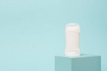 White deodorant on the podium, blue background, copy space