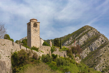 Fototapeta na wymiar Old Bar (Stari Bar) fortress in Montenegro with a watchtower and lush greenery against a mountainous backdrop