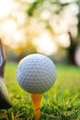 The golf ball sits on a yellow tee with bokeh lights on the back.