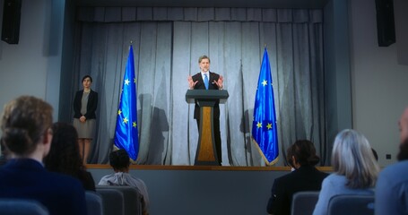 Confident politician makes an announcement, delivers campaign speech, gives interview to journalists and media. Mature representative of the European Union performs at press conference. Election day. - obrazy, fototapety, plakaty