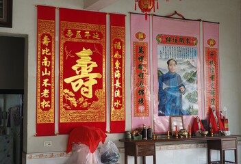 Portrait of Chairman Mao Ze Dong hanging on a wall above a shrine in a house in Hubei, China