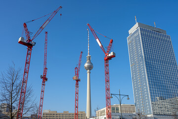 The famous Television Tower of Berlin, a skyscraper and four red tower cranes
