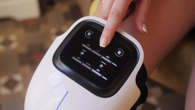 Girl athlete uses a modern massage for therapeutic relaxation of the knee. The concept of sports recovery after training and injury.