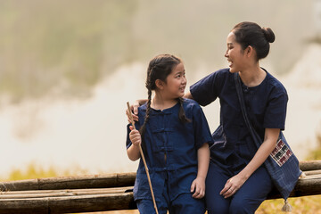 Young Asian mother with daughter wearing indigo clothing spending time outdoors, family relationship