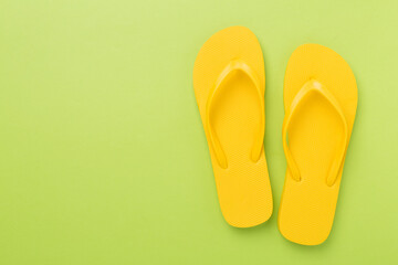 Bright yellow flip-flops on color background, top view. Summer concept