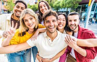 Multiracial young people hugging together smiling at camera outside - Youth community concept with...