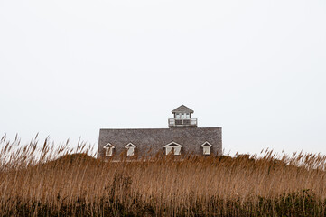 Oregon Inlet Life Saving Station behind dune grass against a white sky