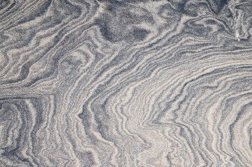Fototapeta na wymiar Full frame of dark swirl patterns in the sand