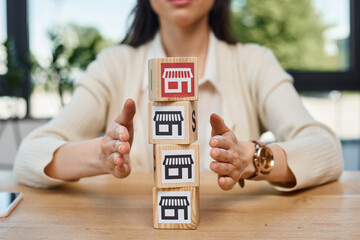 A businesswoman sits at a table, engaging in a franchise concept, with a stack of blocks...