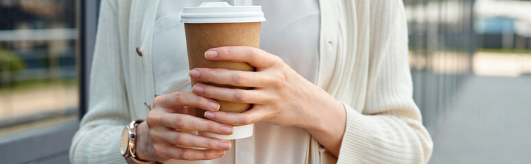 A businesswoman enjoys a quiet moment holding a cup of coffee in a modern outdoor office setting.