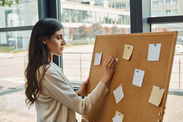 A dynamic female entrepreneur stands confidently in front of a board filled with strategic plans...