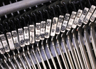 intricate metal levers and embossed characters on an antique typewriter.