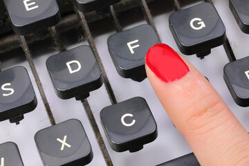 index finger with nail polish of an office secretary typing the key in the typewriter - obrazy, fototapety, plakaty