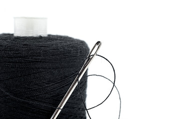 A spool of black thread and a needle on a white background. Thread isolate. Sewing accessories....