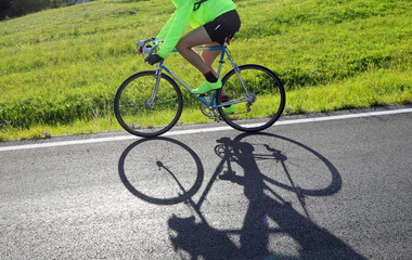 cyclist pedals a racing bike on a mountain road, his shadow on the asphalt