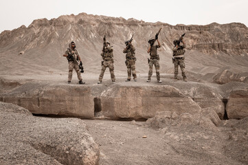 Soldiers in camouflage uniforms aiming with their rifles.ready to fire during military operation in...