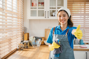 Smiling woman in uniform apron and rubber glove ready for home cleaning. Emphasizing housekeeping...