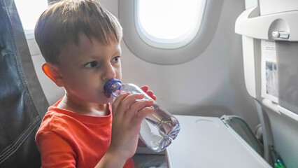 Little kid drinking water in airplane during long flight