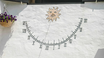 Menorca, Spain - August 20 2023: Sundial with hours painted on wall with wooden stick shadow...