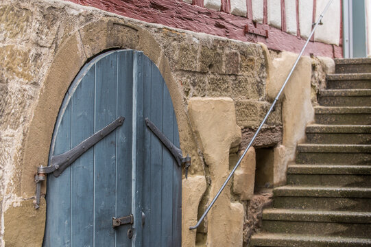H&ouml;lzernes Kellertor vor steinernem Rundbogen aus Sandstein an Fachwerkhaus mit Treppe und Treppengel&auml;nder in Weinstadt-Str&uuml;mpfelbach.