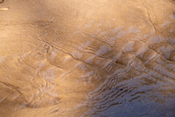 Water ripples on the sand at the beach. Abstract background.