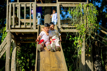 Two brothers embrace each other down a handmade wooden slide.