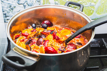 Sliced plum berries are boiled in a large saucepan. Making fruit jam, preserving and preparing for the winter