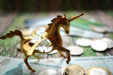 A unicorn statuette with coins on the table. © Станислав 