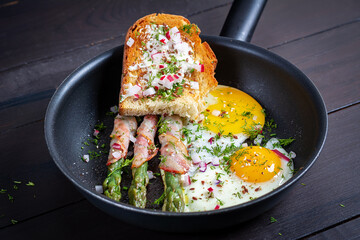 Keto breakfast. Fried eggs  with asparagus in bacon and toast. - 782317841
