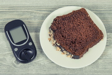 Glucose meter and sweet chocolate cake. Checking sugar level during diabetes