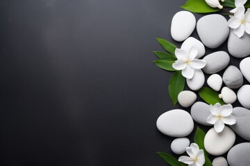 Top view of white flowers with smooth pebbles on dark background. Copy space, spa concept