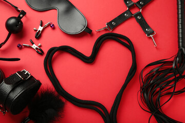 BDSM set on red background. BDSM accessories and rope in the shape of a heart. Mask, handcuffs,...