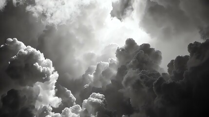 A grayscale image of storm clouds. The clouds are dense and appear to be building. The image has a dark and ominous feel to it.