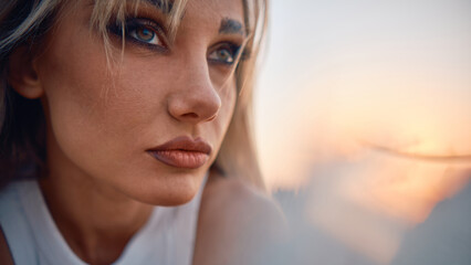 A thoughtful and emotionally evocative close-up of a woman's face against the backdrop of a sunset