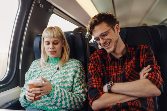 A young couple is sitting in a train and talking during travel.