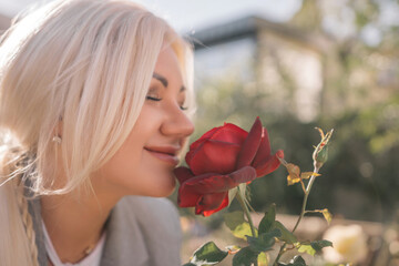 A woman is smelling a red rose. Concept of happiness and contentment, as the woman is enjoying the...