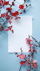 A mockup with a white paper and beautiful blooming red flowers on a blue background