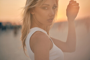 A delicate side profile of an elegant woman against the warm light of the setting sun